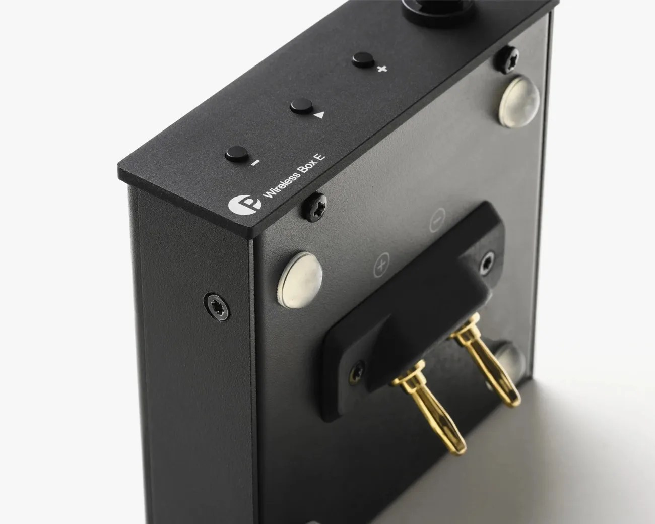 Black rectangular wireless audio device with gold speaker terminals and control buttons on top.
