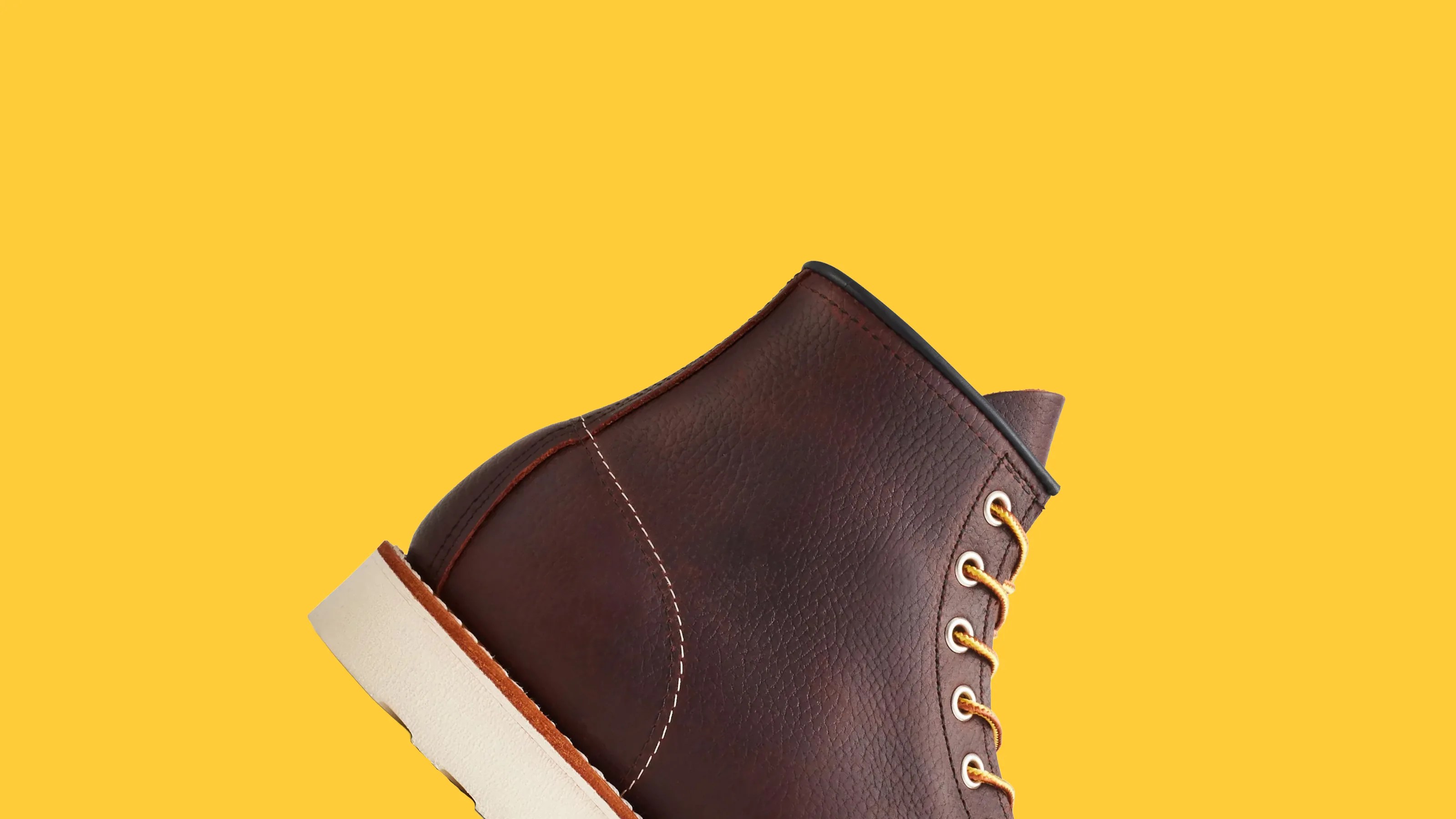Brown leather boot with yellow laces and white sole on a yellow background.