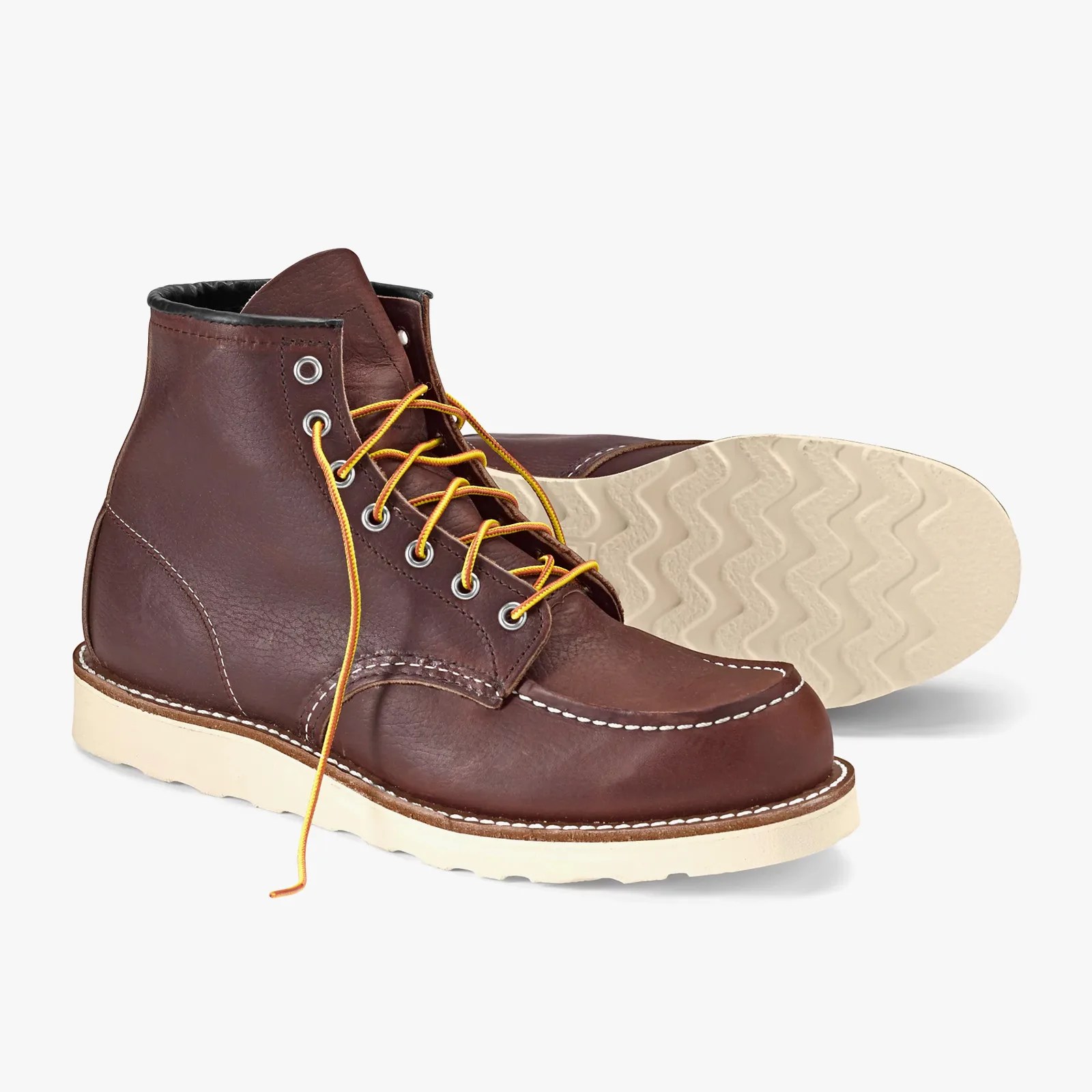 Brown leather moc toe boots with yellow laces and white rubber soles.