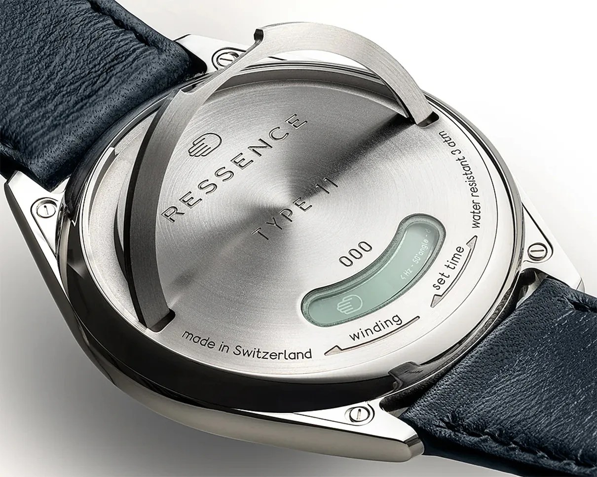Back of a Ressence Type 11 watch with stainless steel case, black leather strap, and engraved instructions.