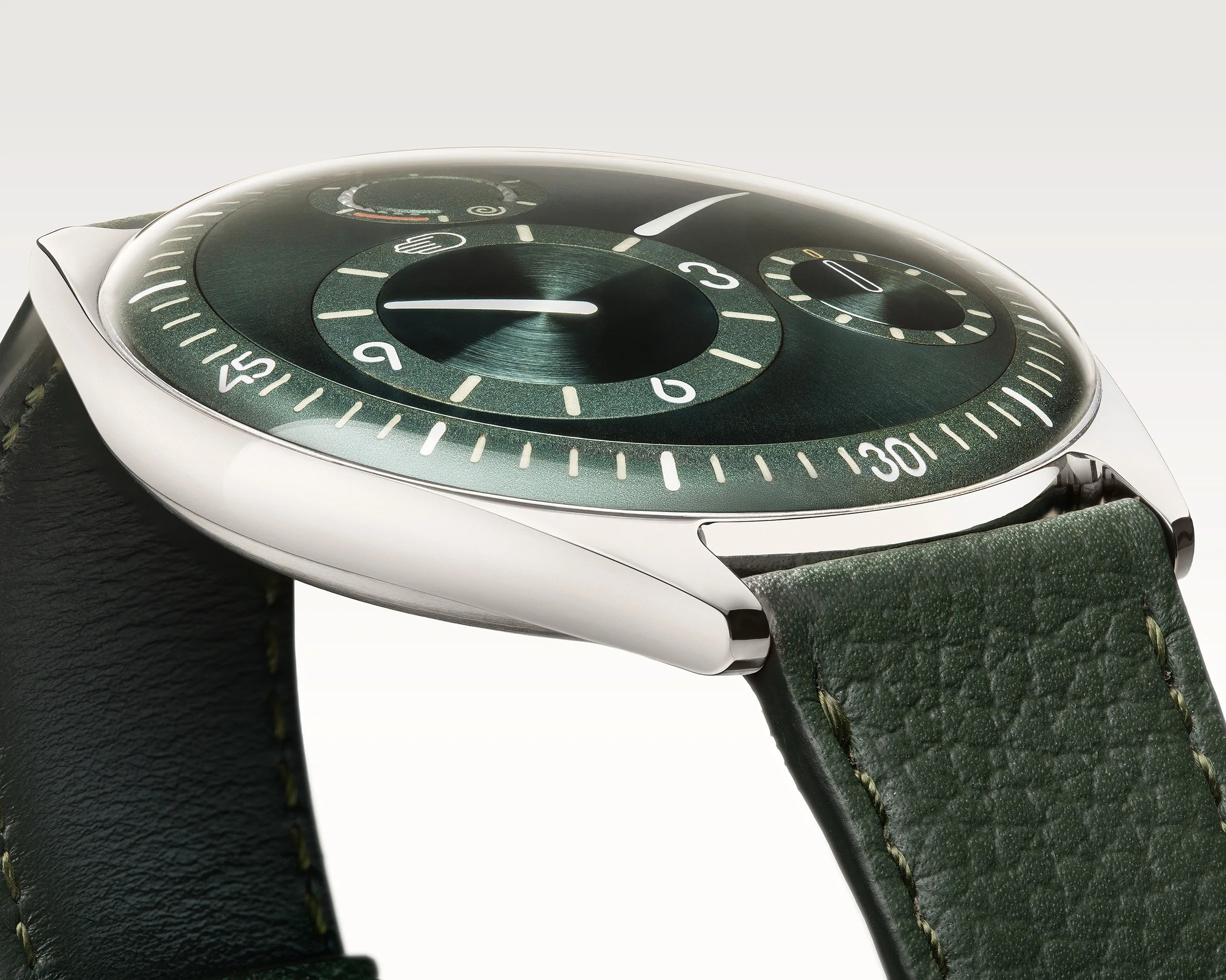 Close-up of a green dial watch with a domed crystal and green leather strap.