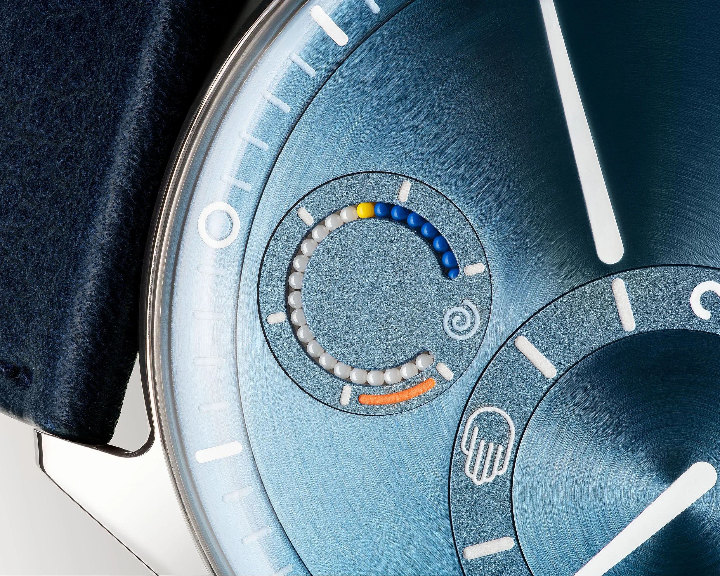 Close-up of a blue watch face with white, blue, yellow, and orange bead indicators and a dark blue leather strap.