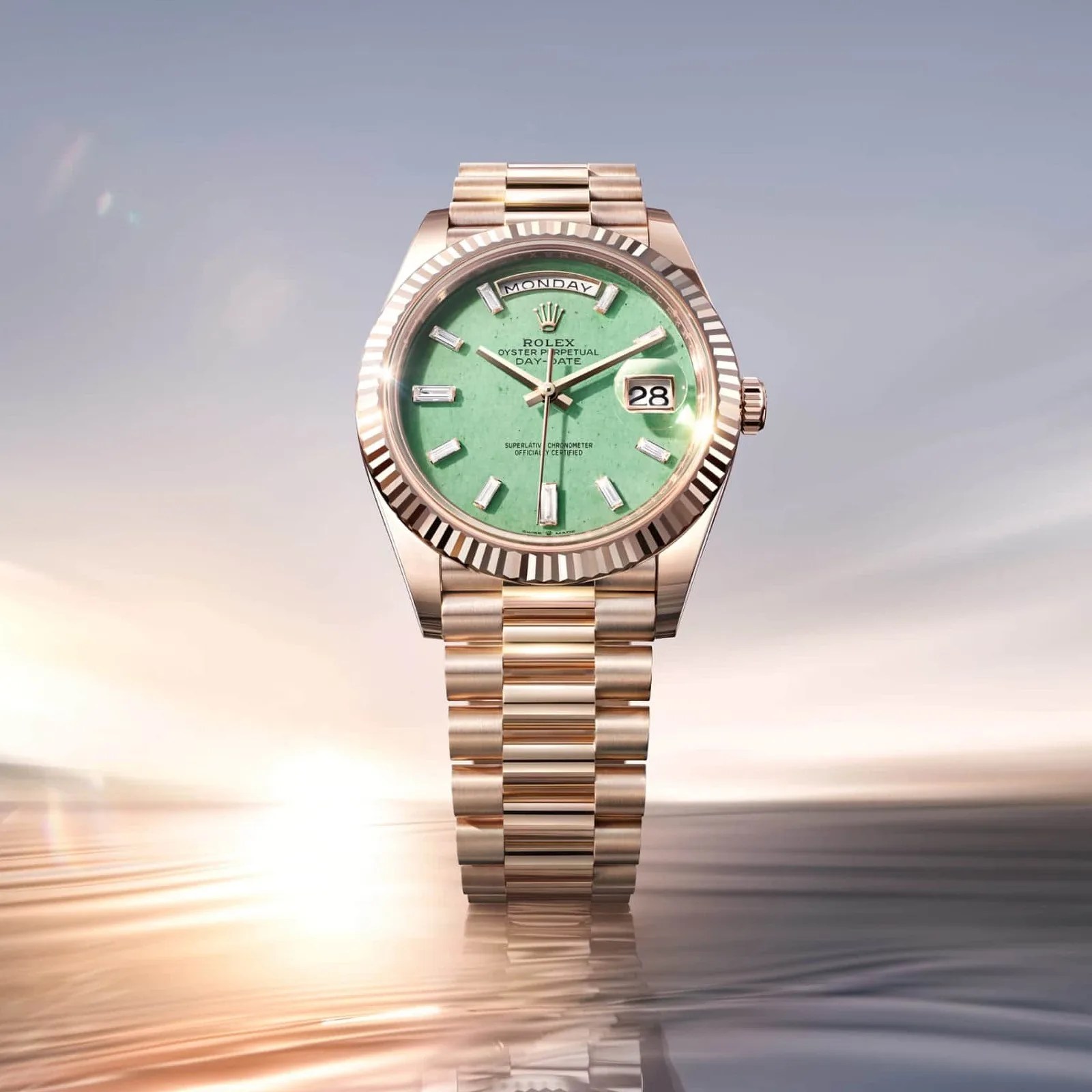 Rolex Oyster Perpetual Day-Date watch with a rose gold bracelet and green dial showing day and date.