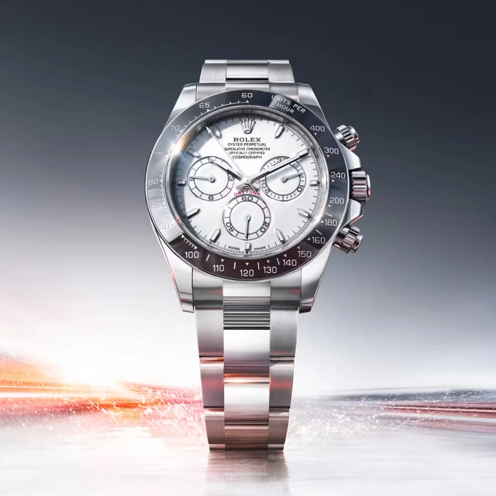 Stainless steel Rolex Daytona watch with white dial and black ceramic bezel on a reflective surface.