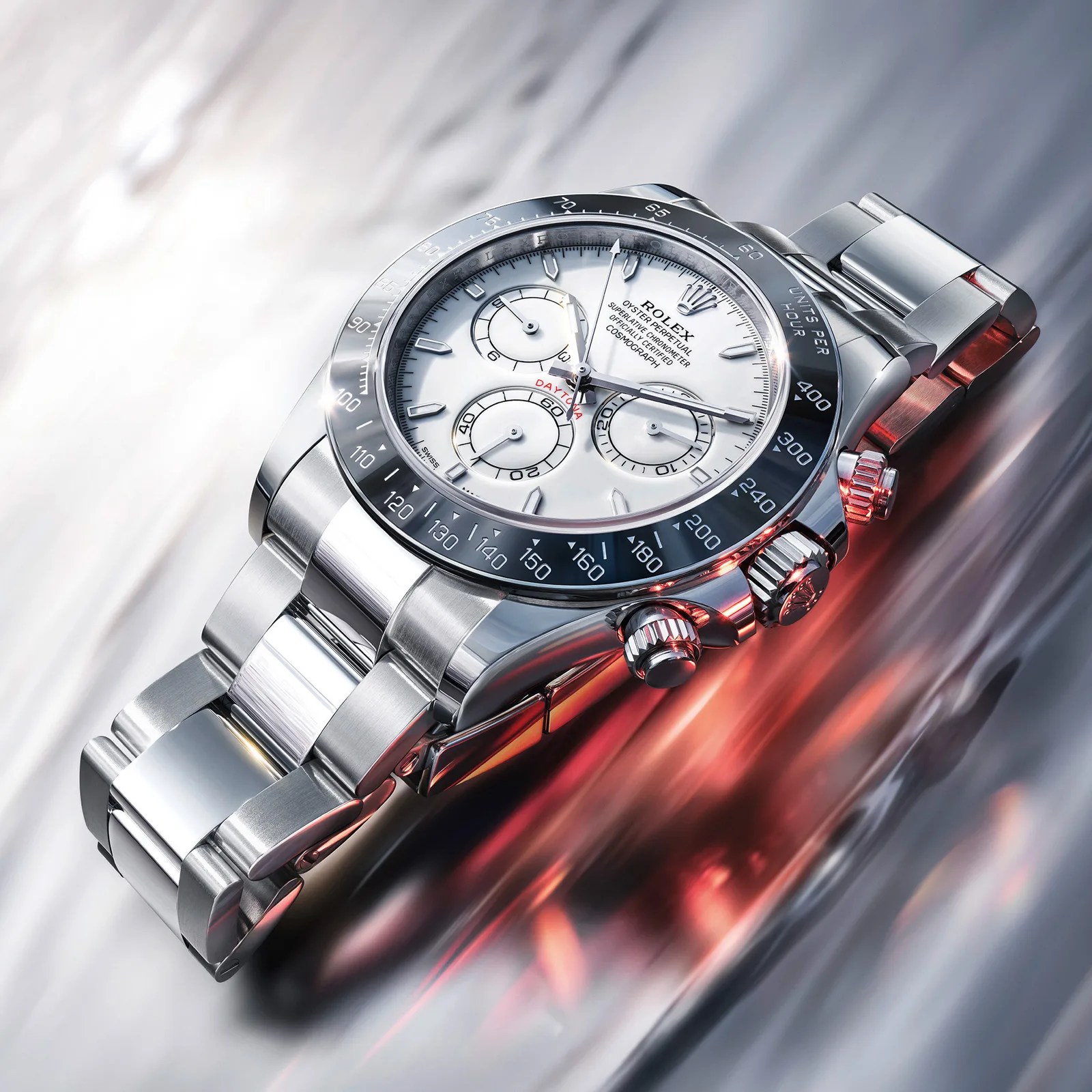 Stainless steel Rolex Daytona watch with white dial and black ceramic bezel on reflective surface.
