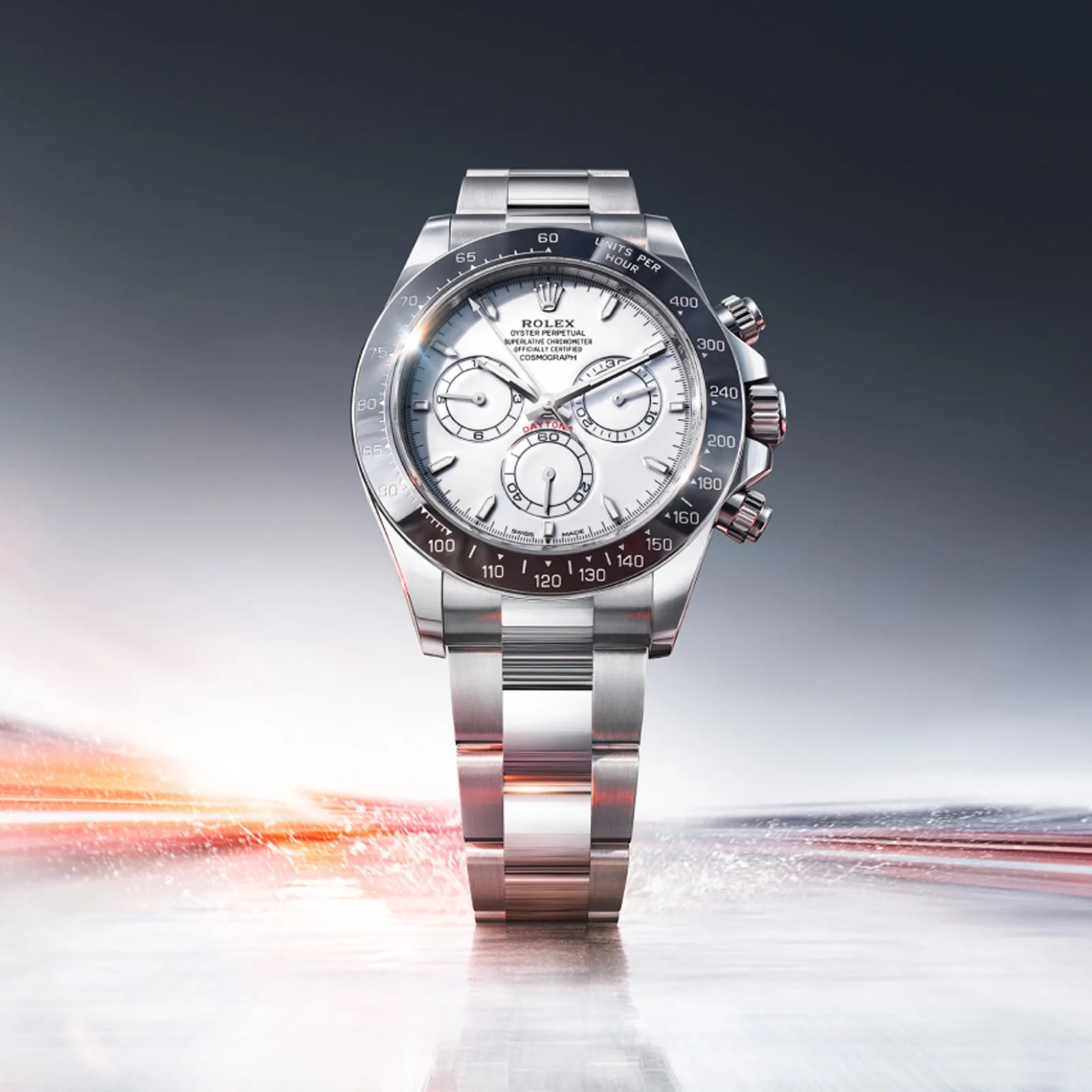 Stainless steel Rolex Daytona watch with white dial and black tachymeter bezel on a reflective surface.