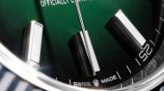 Close-up of a green watch dial with rectangular silver hour markers and "Swiss Made" text near the bottom.