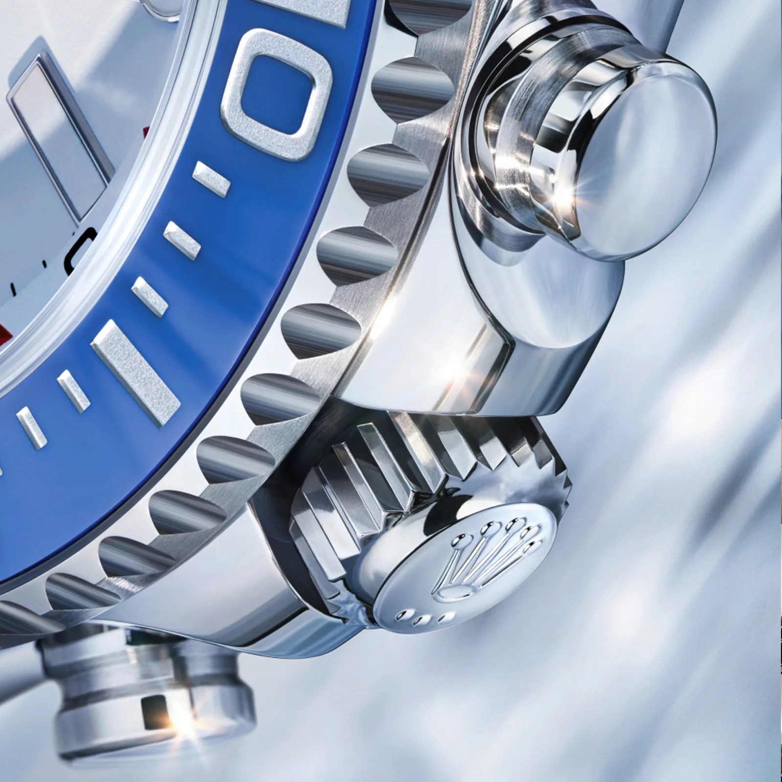 Close-up of a polished stainless steel watch crown and bezel with blue and silver detailing and the Rolex logo on the crown.