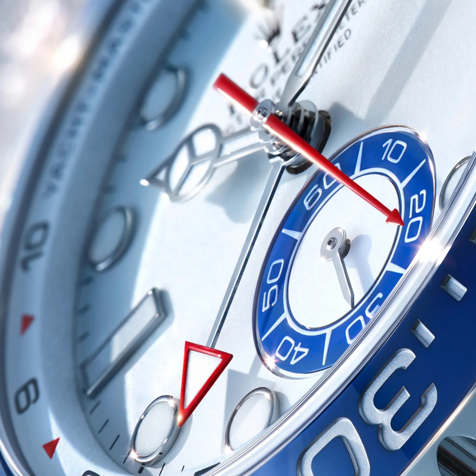 Close-up of a silver Rolex watch face with blue and red accents and luminous hour markers.