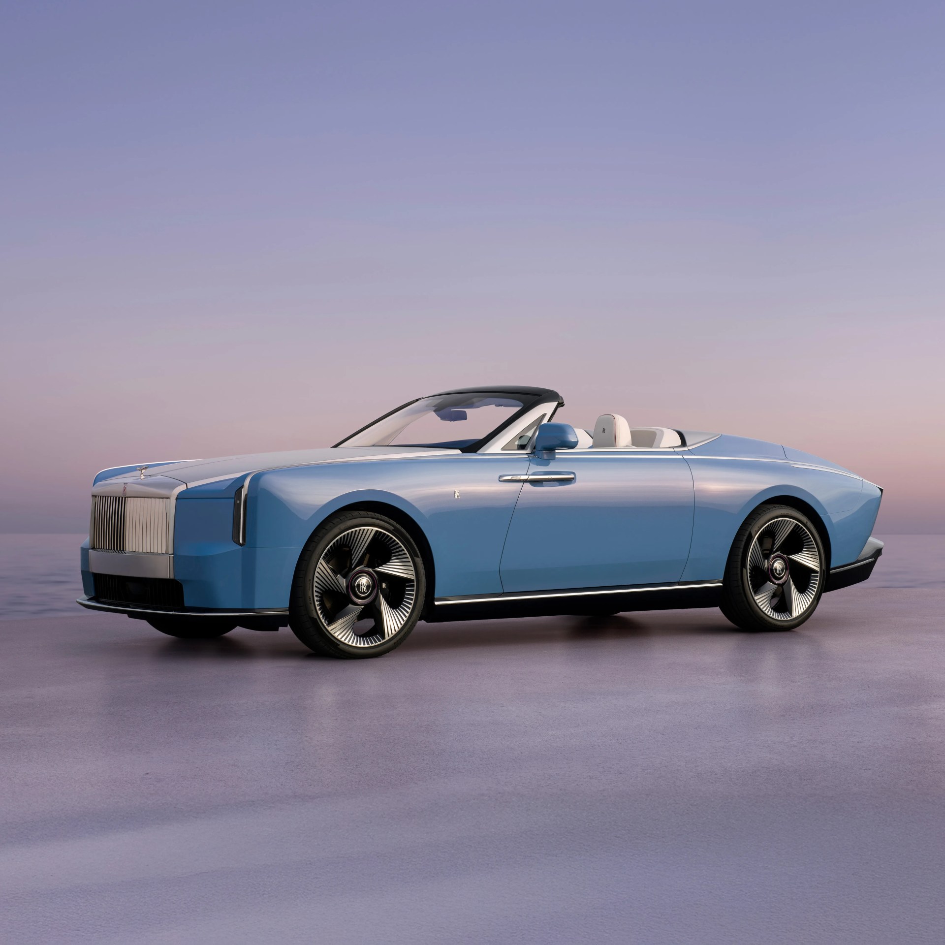 Light blue Rolls-Royce convertible with black and silver wheels on a smooth reflective surface at sunset.