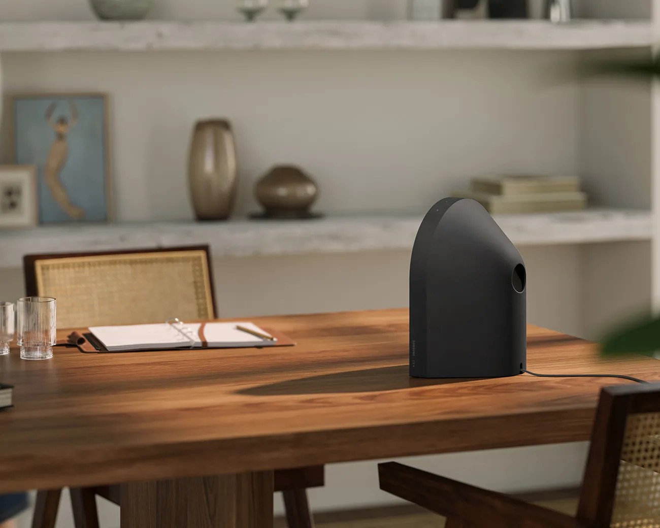 Matte black, modern, cone-shaped humidifier with a power cord on a wooden table in a dining room.