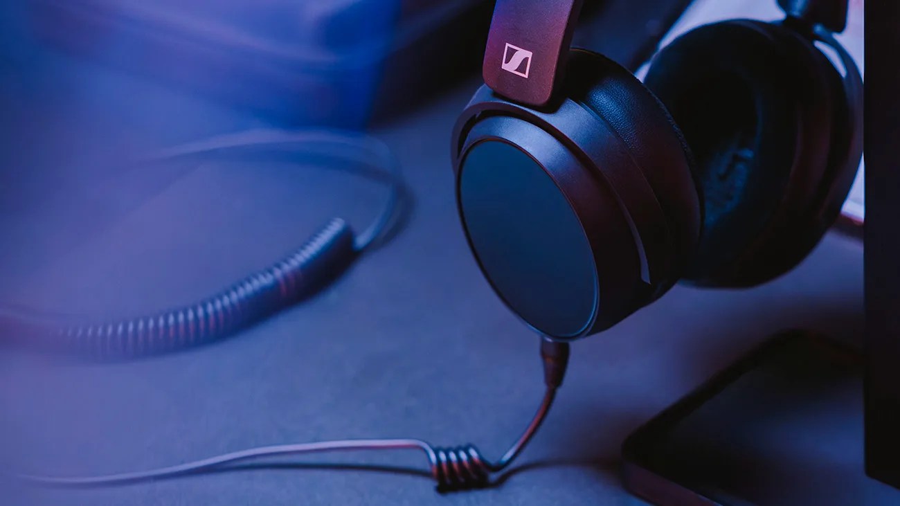 Black over-ear Sennheiser headphones with coiled cable resting on a dark surface.