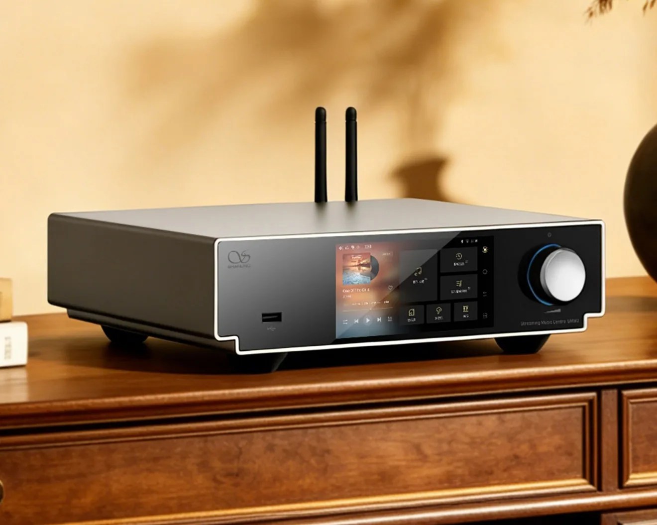 Black and silver streaming music center with touchscreen and two antennas on a wooden cabinet.