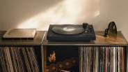Black Sony turntable on a metal shelf with vinyl records and decorative objects.
