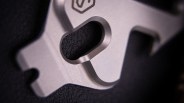 Close-up of a textured black rubber piece set in a silver metal frame with a cutout.