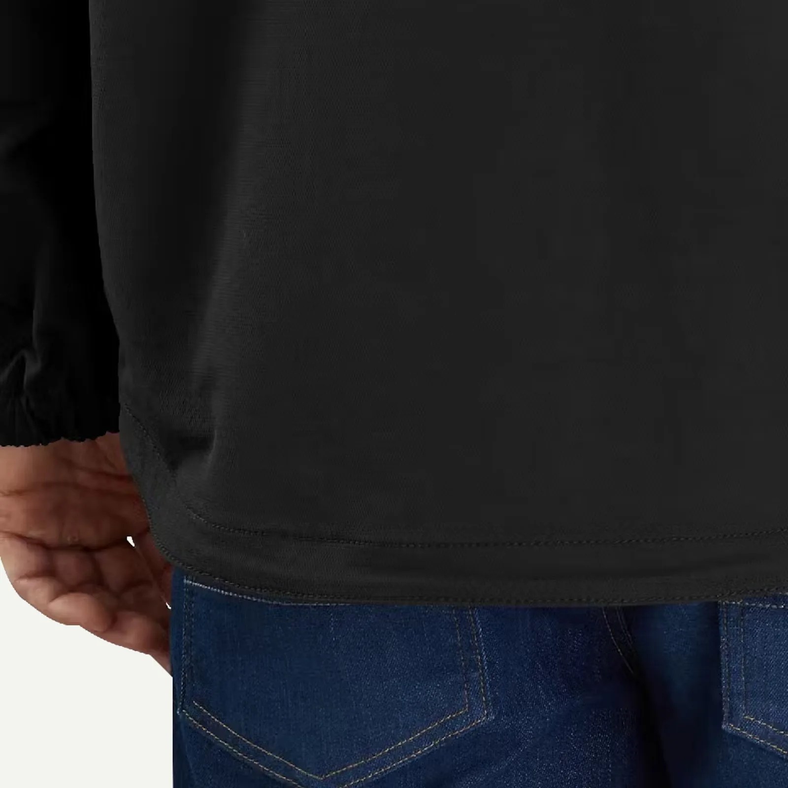 Close-up of a person wearing a black long-sleeve shirt and blue denim jeans, showing the shirt hem and back pocket area.