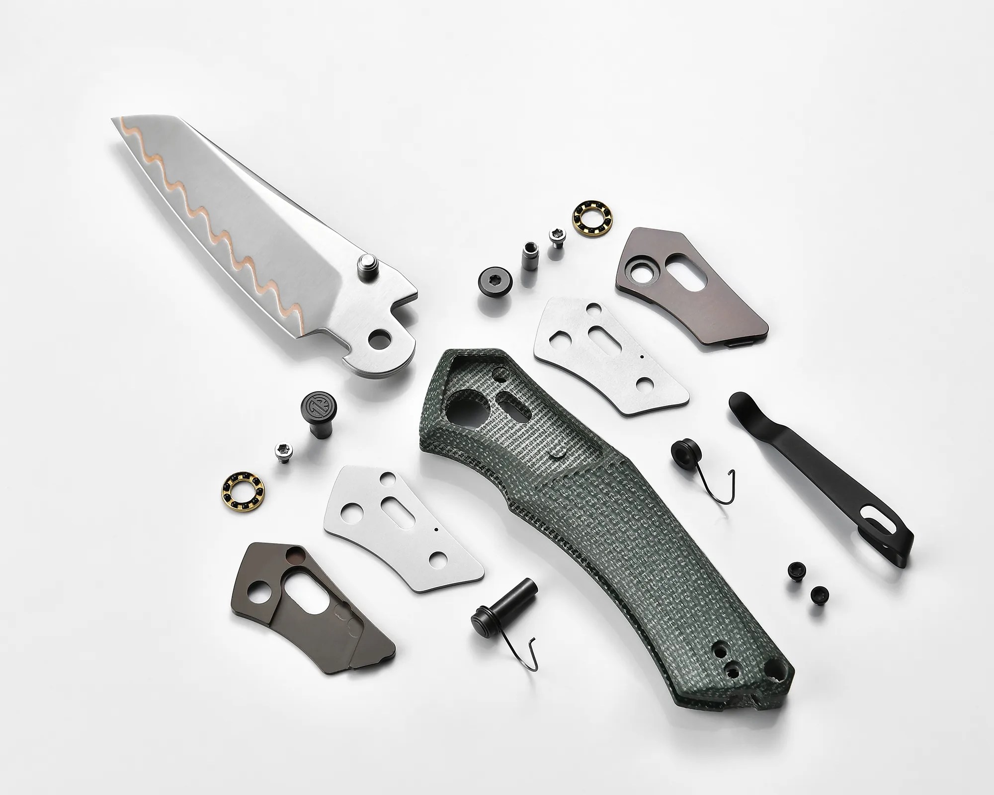 Disassembled folding knife with a textured green handle, a partially serrated blade, metal liners, screws, and a black pocket clip on a white background.