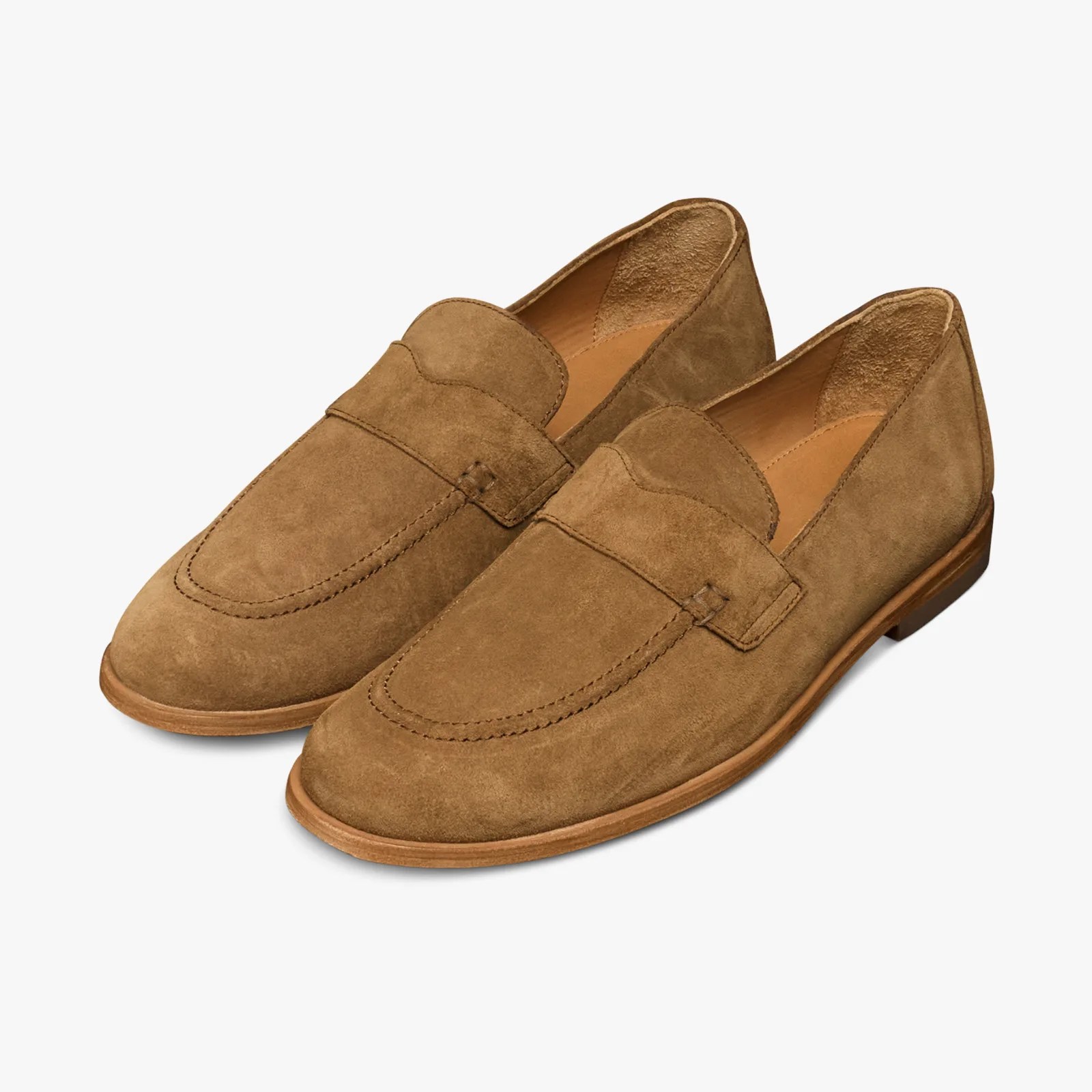 Pair of tan suede loafers with stitched detailing and wooden soles on a white background.