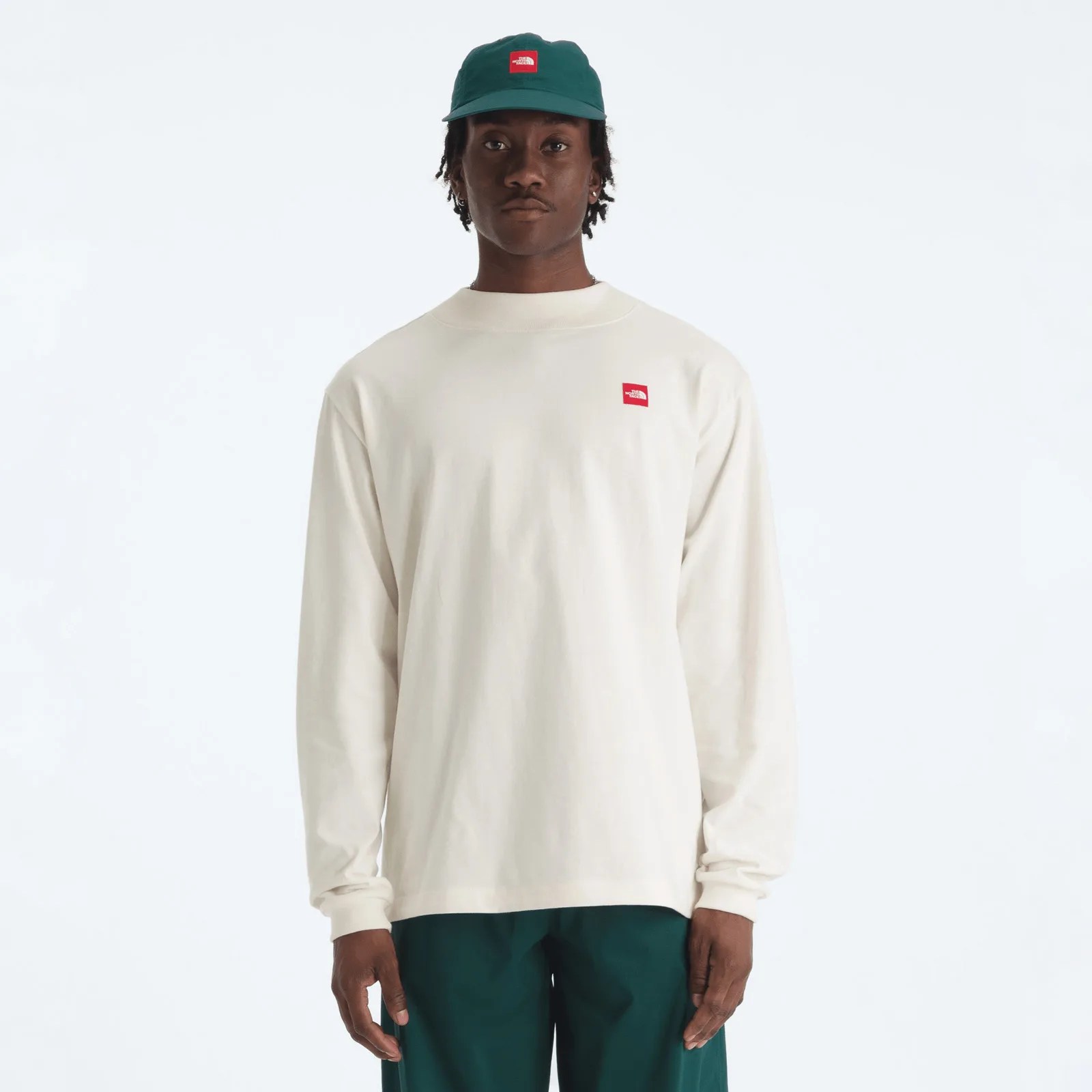 Off-white long-sleeve shirt with a small red The North Face logo on the chest worn by a person.