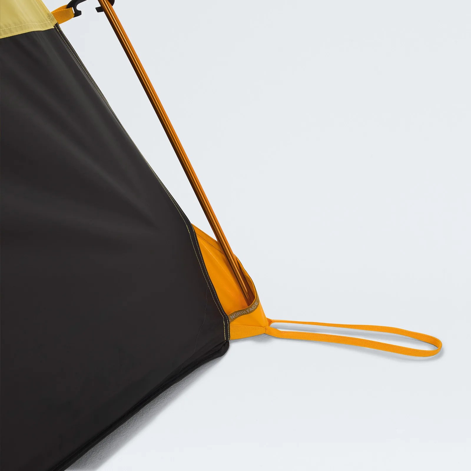 Close-up of a black and yellow tent corner with an orange pole and yellow loop strap on a white background.