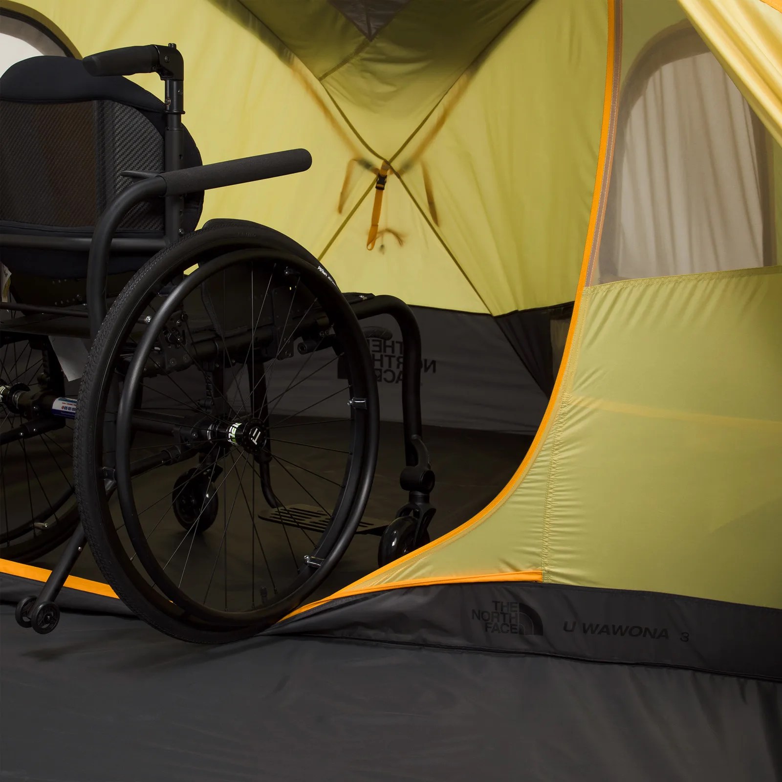 Black wheelchair inside a yellow and gray North Face U Wawona 3 tent.