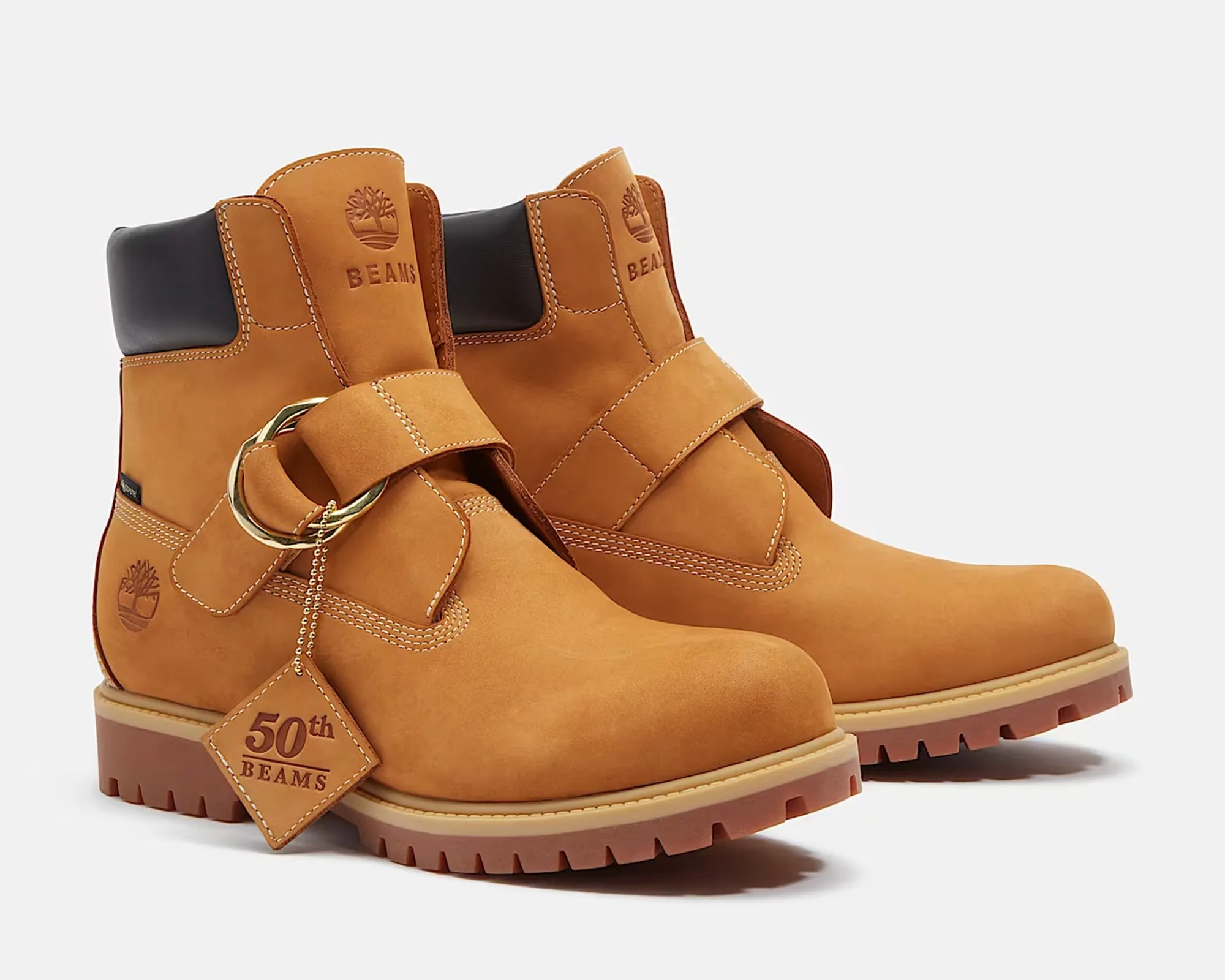 Pair of tan leather ankle boots with black padded collars and a gold buckle strap, featuring "50th BEAMS" tag.