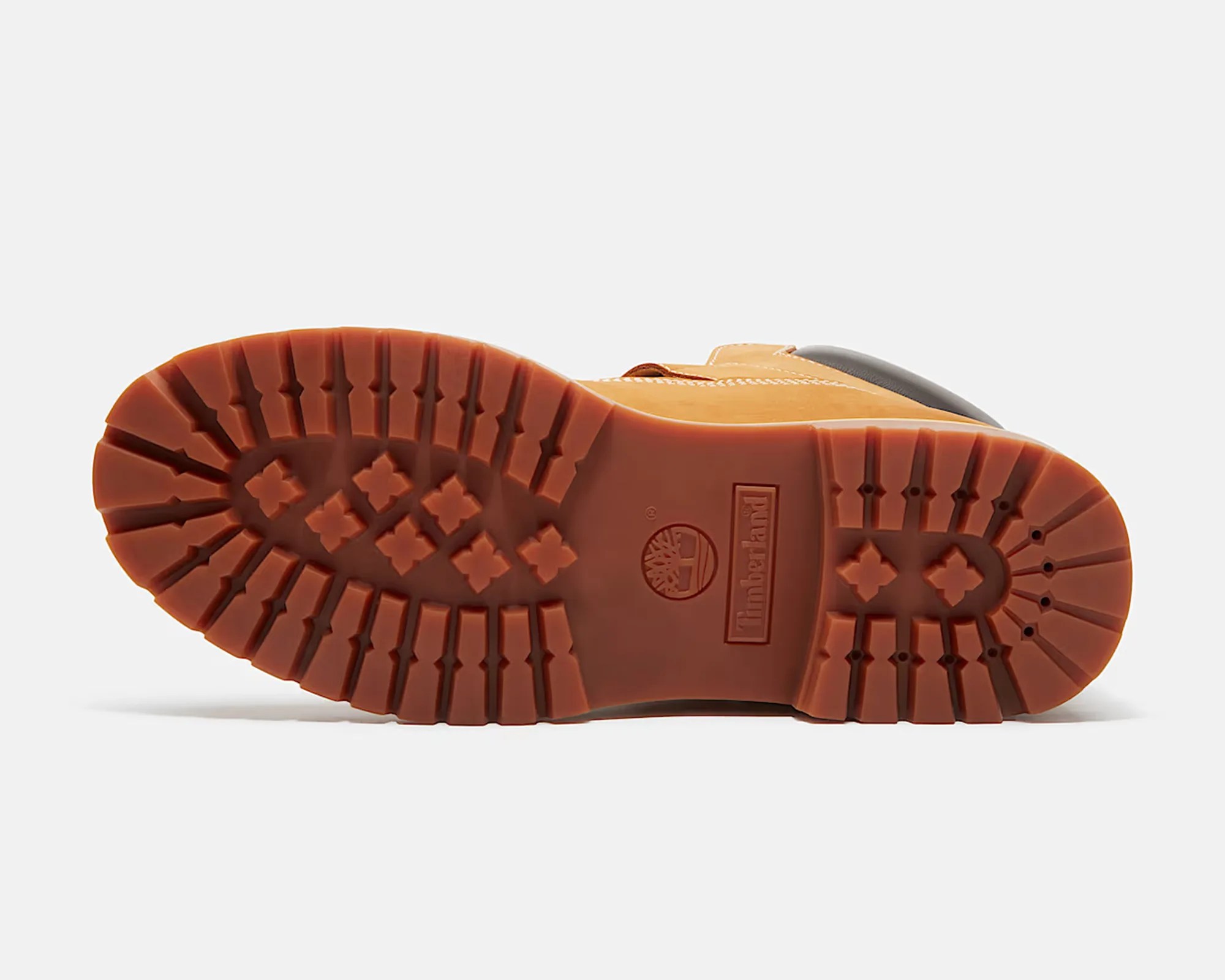 Brown rubber sole of a Timberland boot with deep treads and logo embossed in the center.