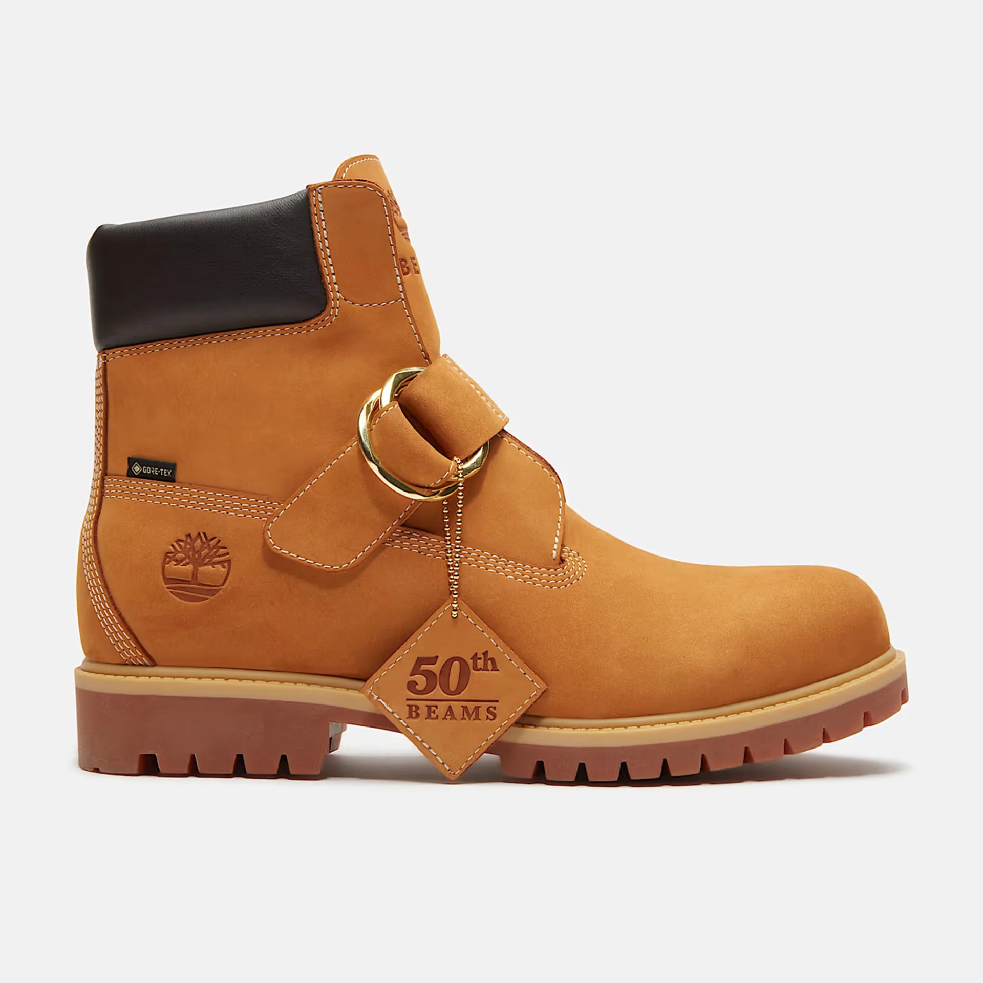 Tan leather ankle boot with black padded collar, gold buckle strap, and "50th BEAMS" leather tag.