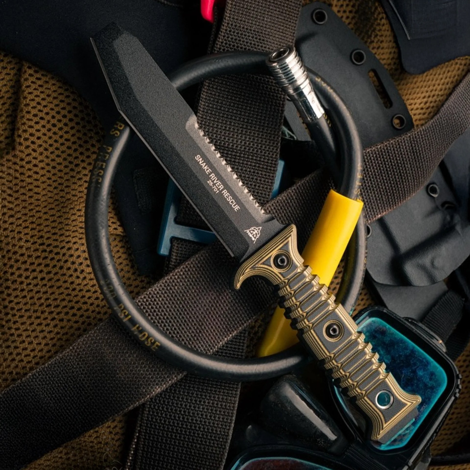 Black Snake River Rescue knife with serrated edge and yellow handle on black straps and brown mesh fabric.