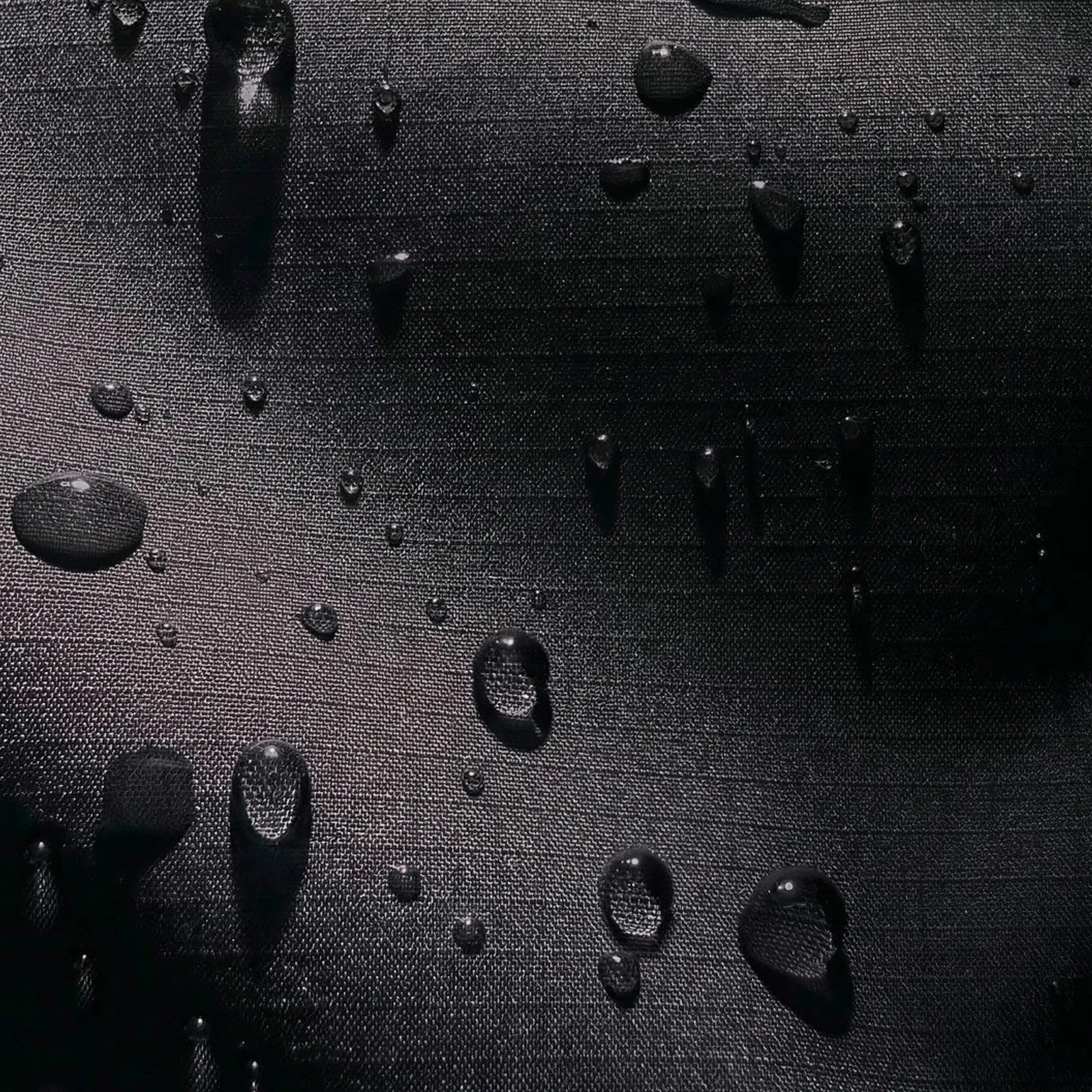 Water droplets on a textured black fabric surface.