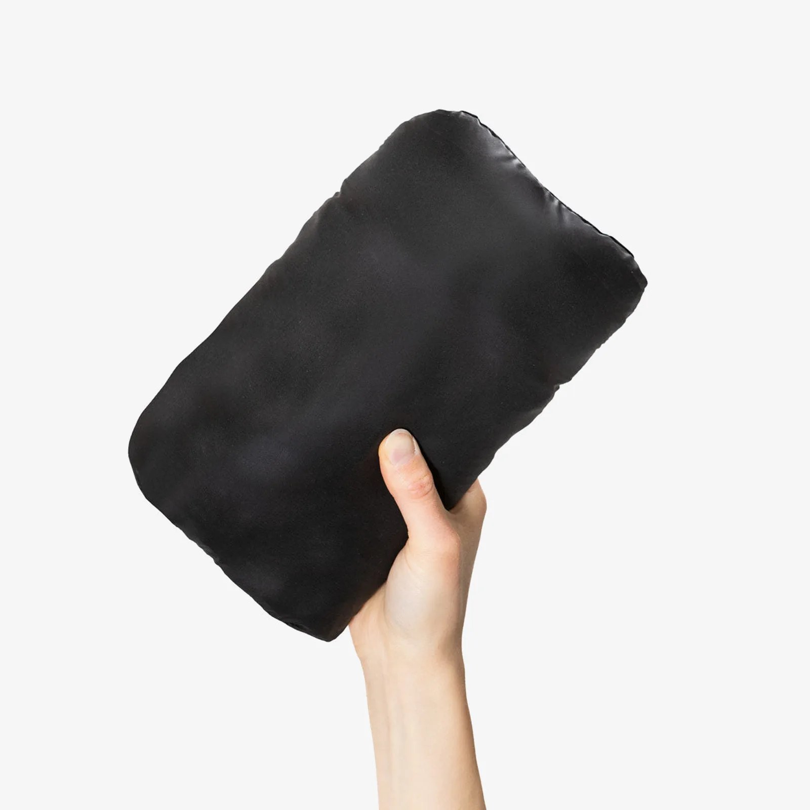 Hand holding a compact, folded black fabric item against a white background.