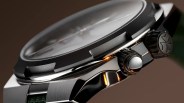 Close-up of a polished titanium watch case with a textured black bezel and two black knurled crowns, one featuring a star emblem.