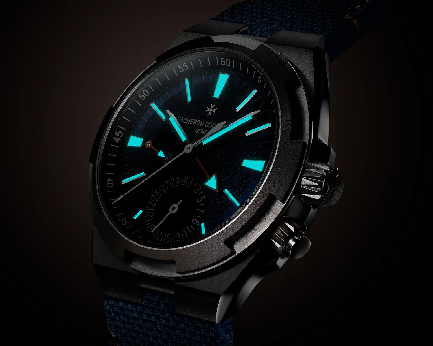 Black metal wristwatch with glowing blue hour markers and hands, featuring a textured blue strap.