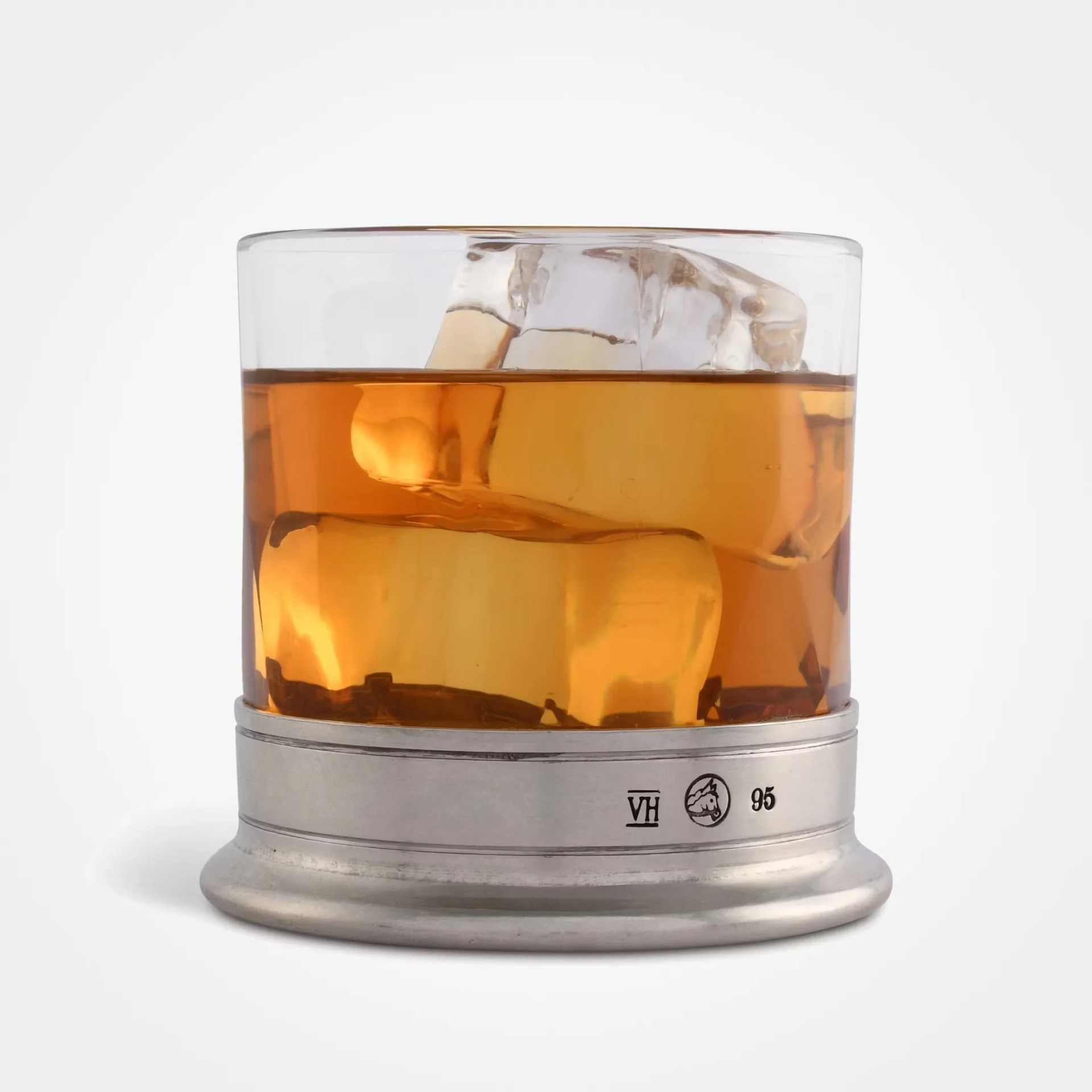 Glass of amber liquid with ice cubes on a metal base with markings "VH," a horse head, and "95.