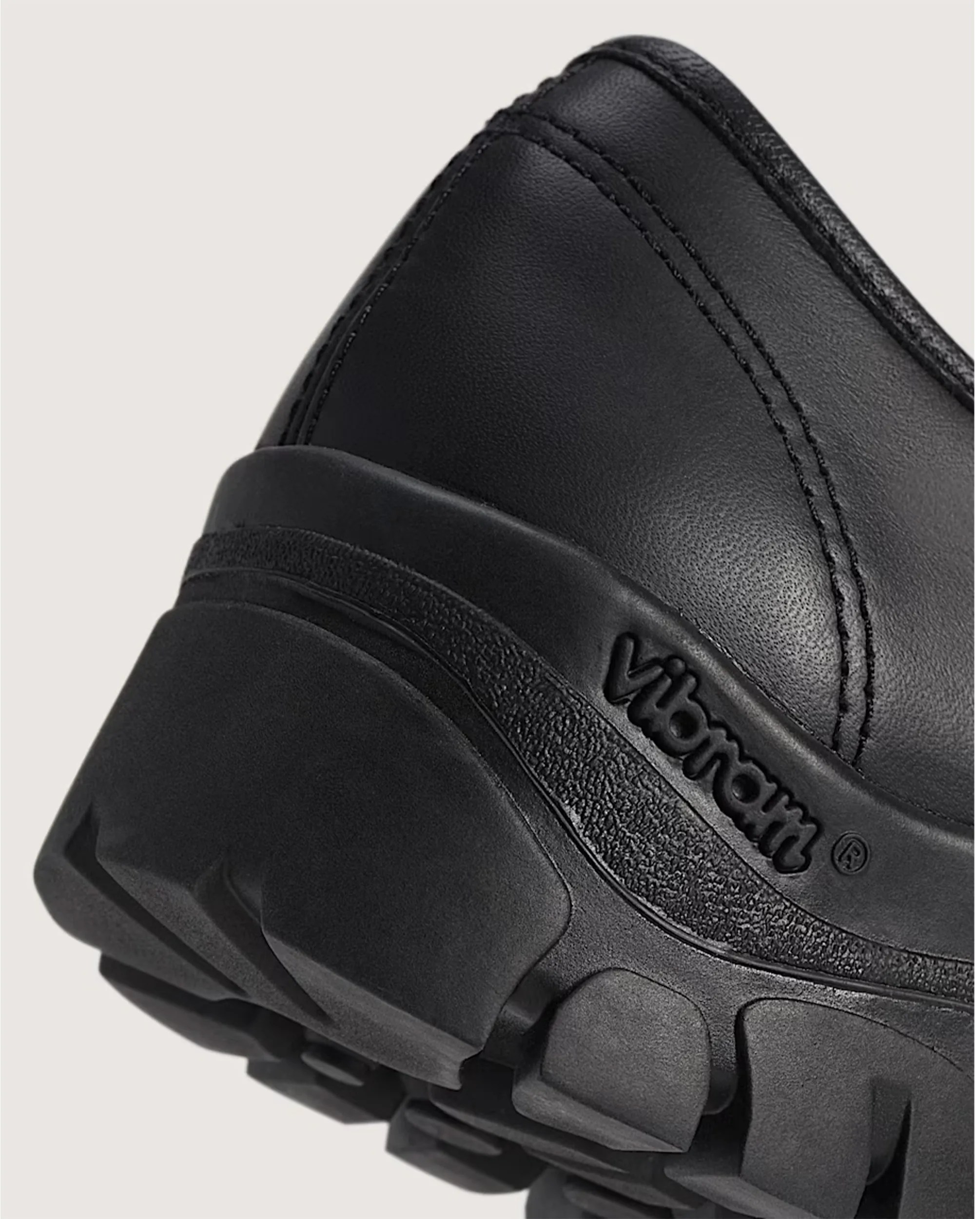 Close-up of black leather shoe heel with textured Vibram rubber sole and embossed Vibram logo.