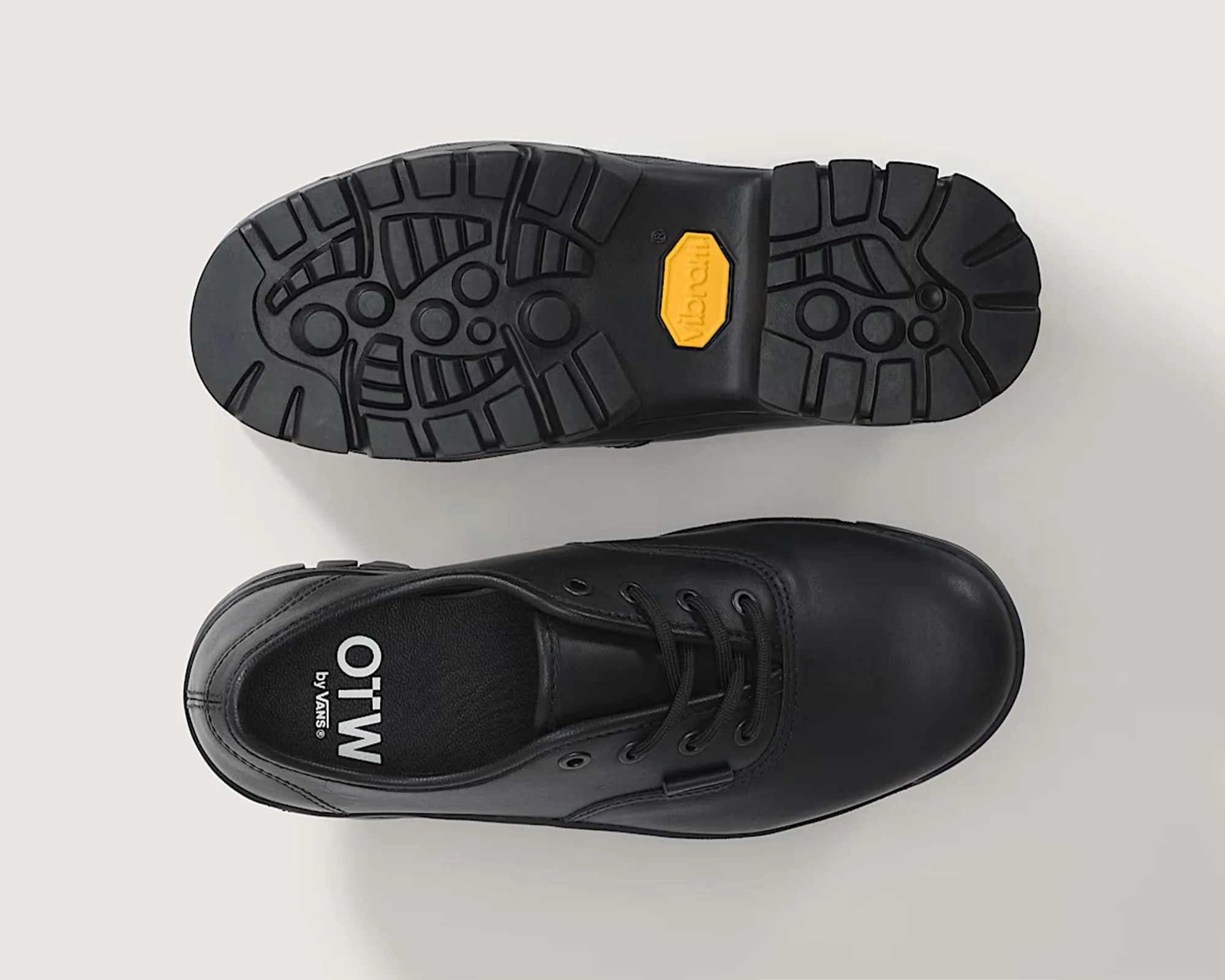 Black leather lace-up shoe with Vibram sole and "OTW by Vans" printed inside.