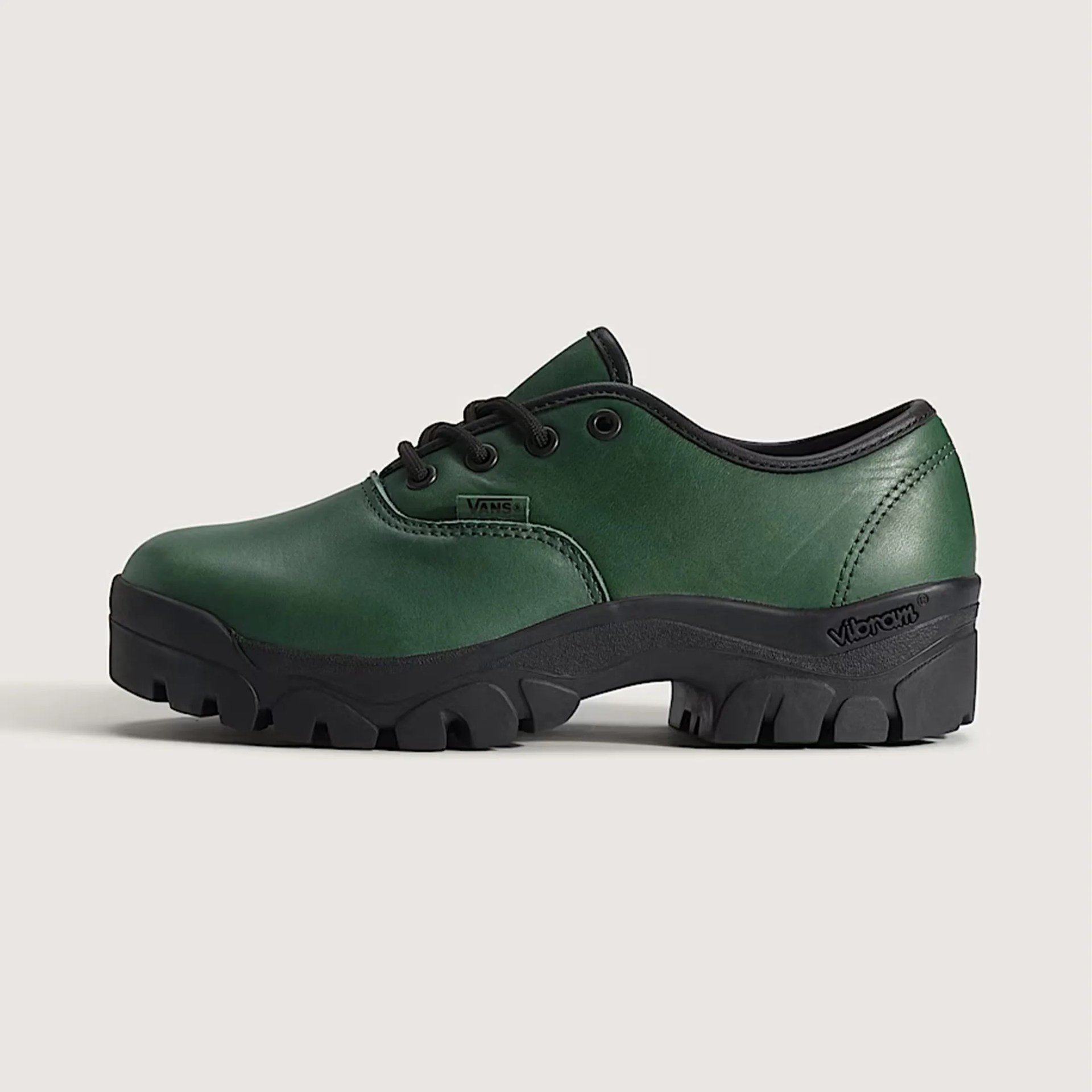 Green leather Vans shoe with black Vibram lug sole and black laces on a neutral background.