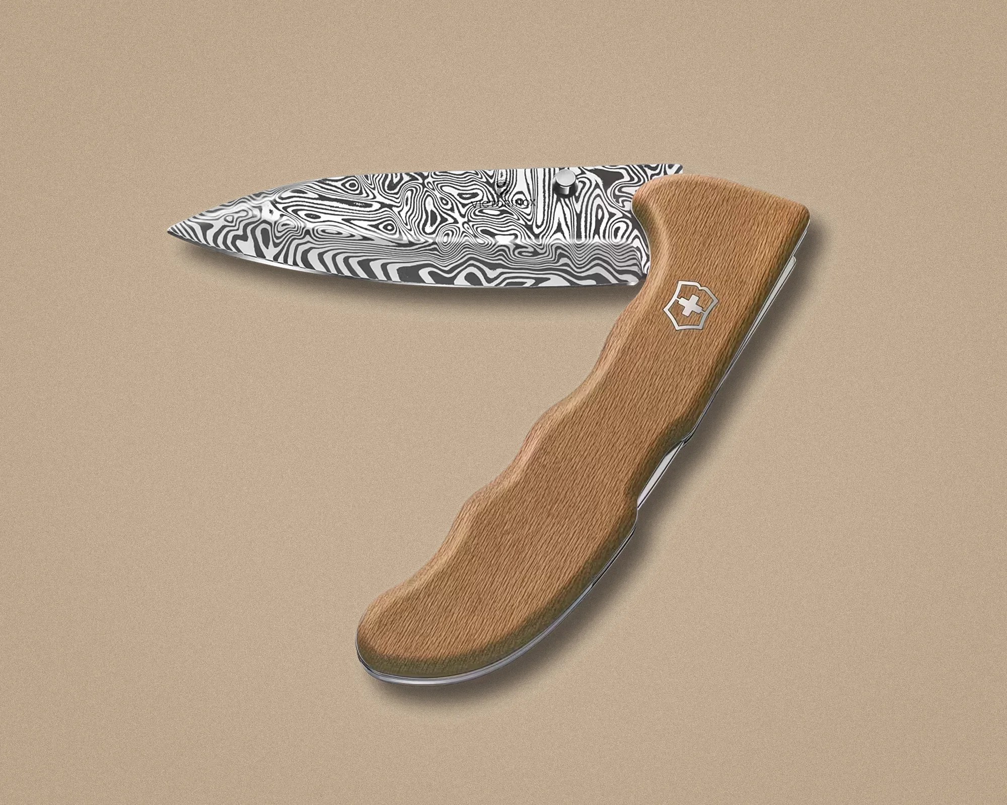 Folding knife with a patterned Damascus steel blade and a wooden handle featuring a silver emblem.