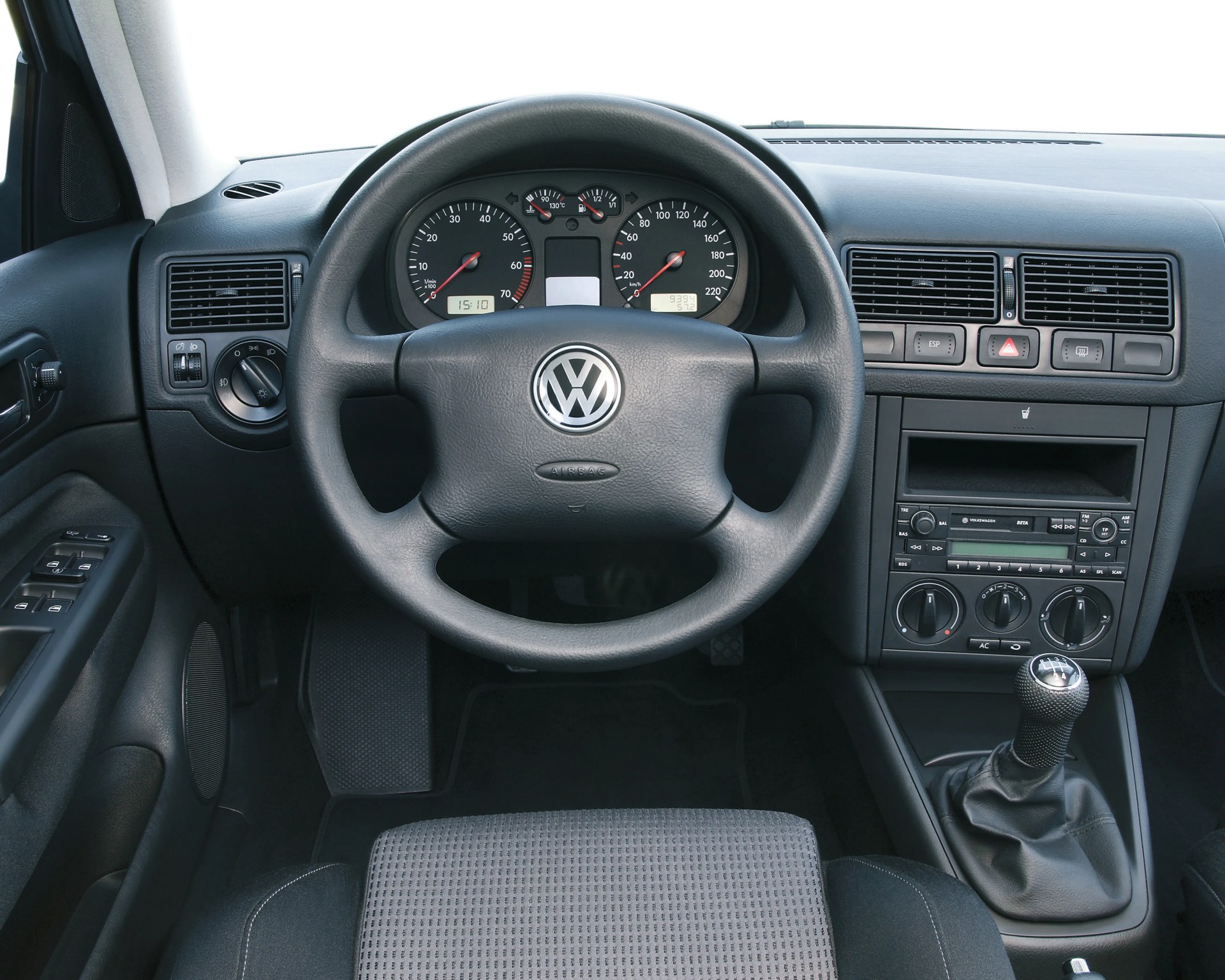 Black Volkswagen steering wheel with dashboard and manual gear shift in a car interior.