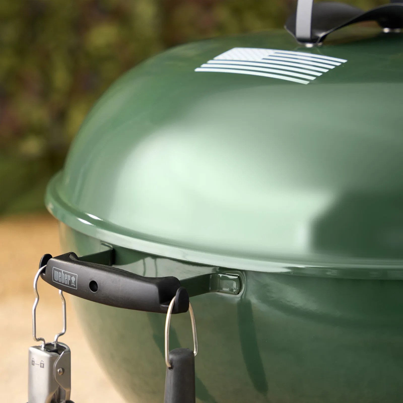 Green Weber kettle grill with black handle and white American flag decal on lid.