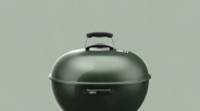 Glossy dark green kettle charcoal grill lid with black handle and Weber logo on front handle.