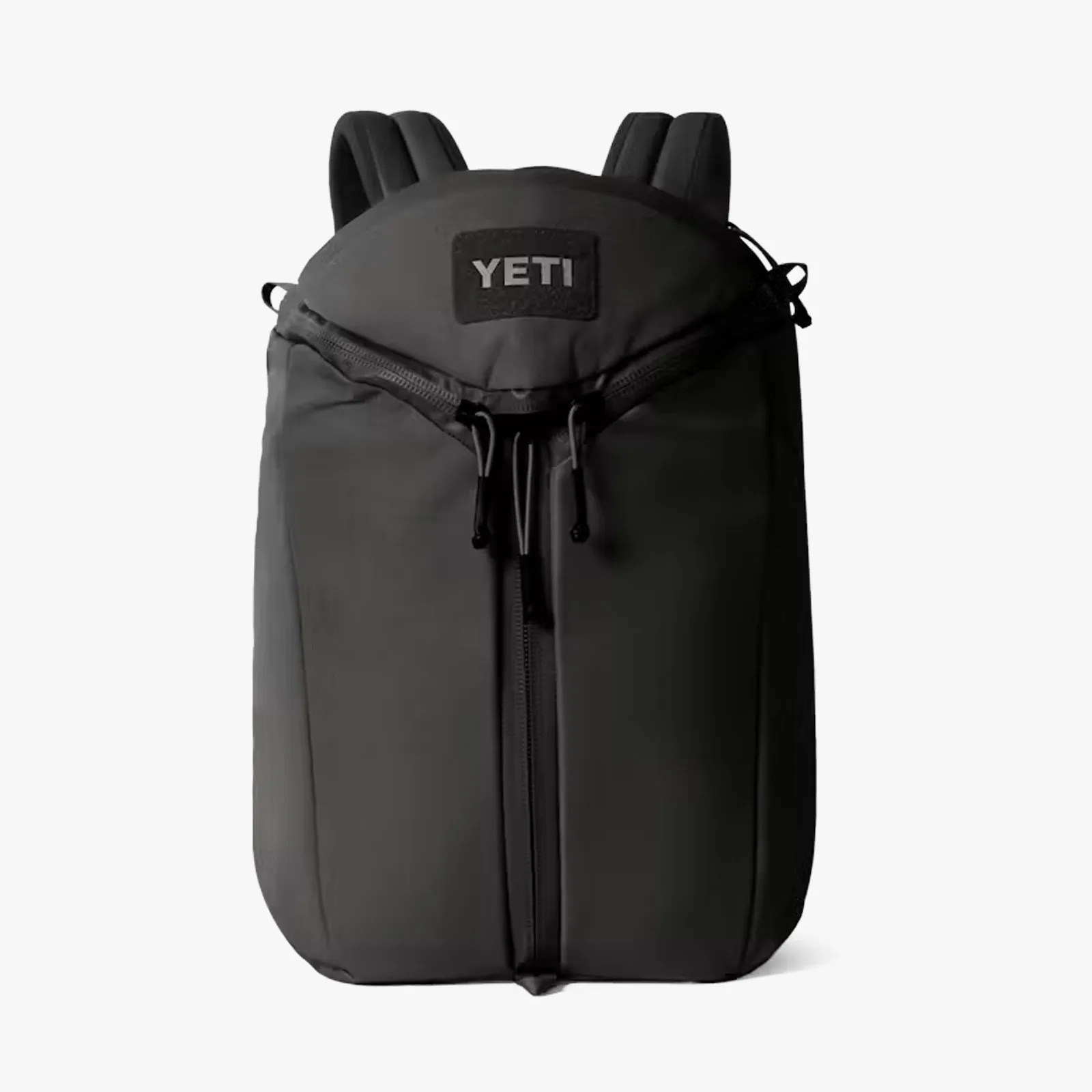 Black YETI backpack with dual zippers and padded shoulder straps on a white background.