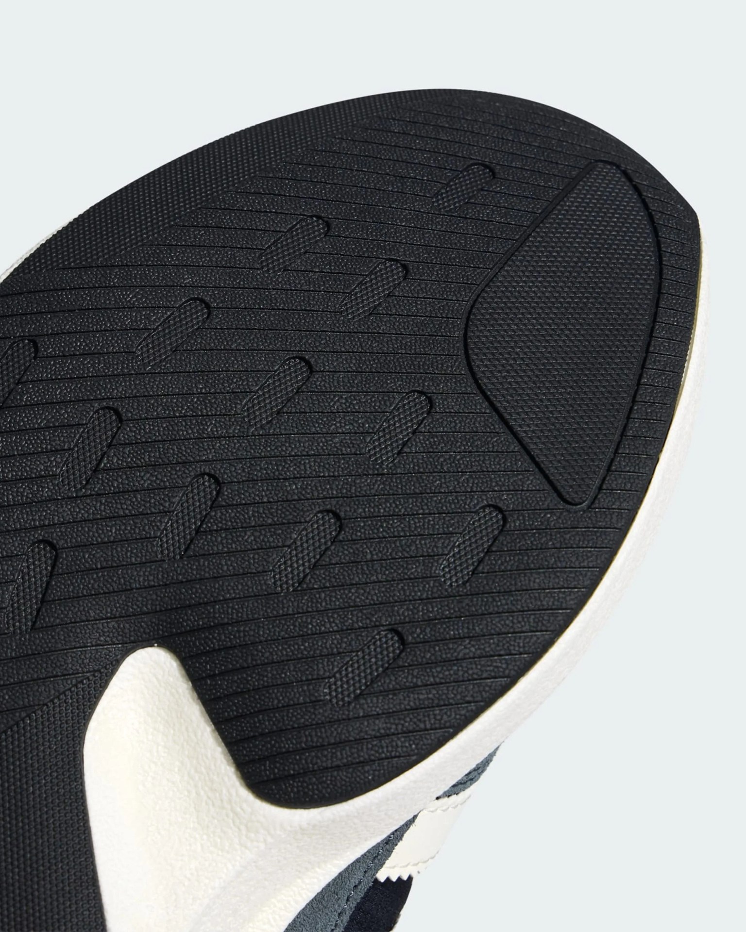 Close-up of a black rubber shoe sole with textured grip patterns and a white midsole edge.