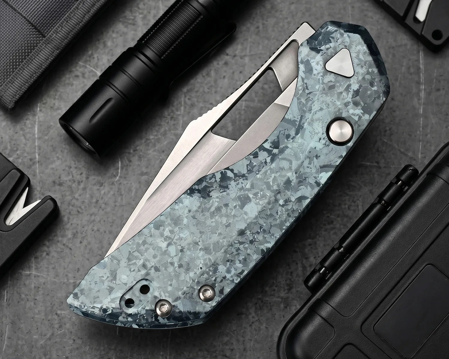 Folded pocket knife with a blue-gray marbled handle and partially visible stainless steel blade on a gray surface.
