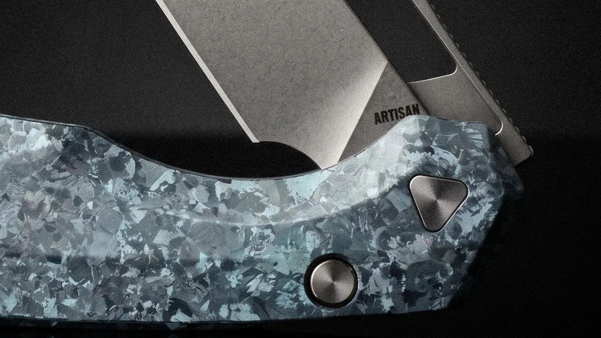 Close-up of a folding knife with a blue patterned handle and a partially visible blade marked "ARTISAN.