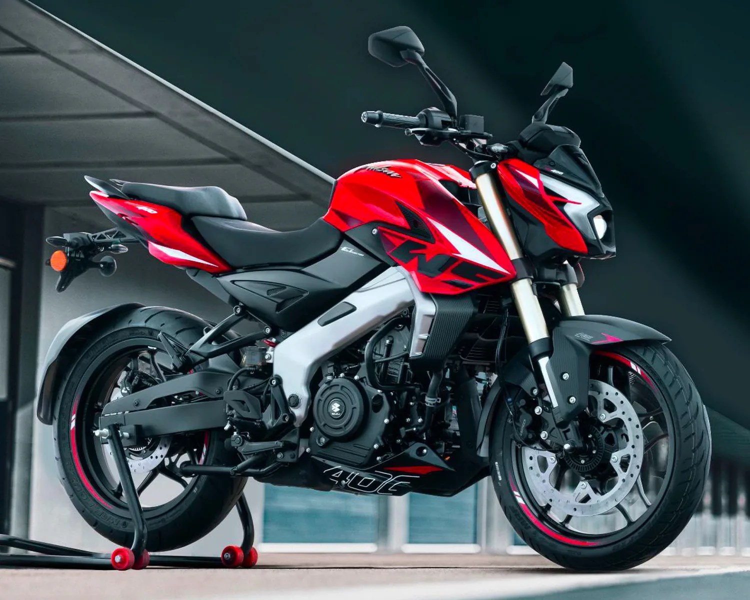 Red and black Suzuki Gixxer 250 motorcycle on a rear stand in a garage.