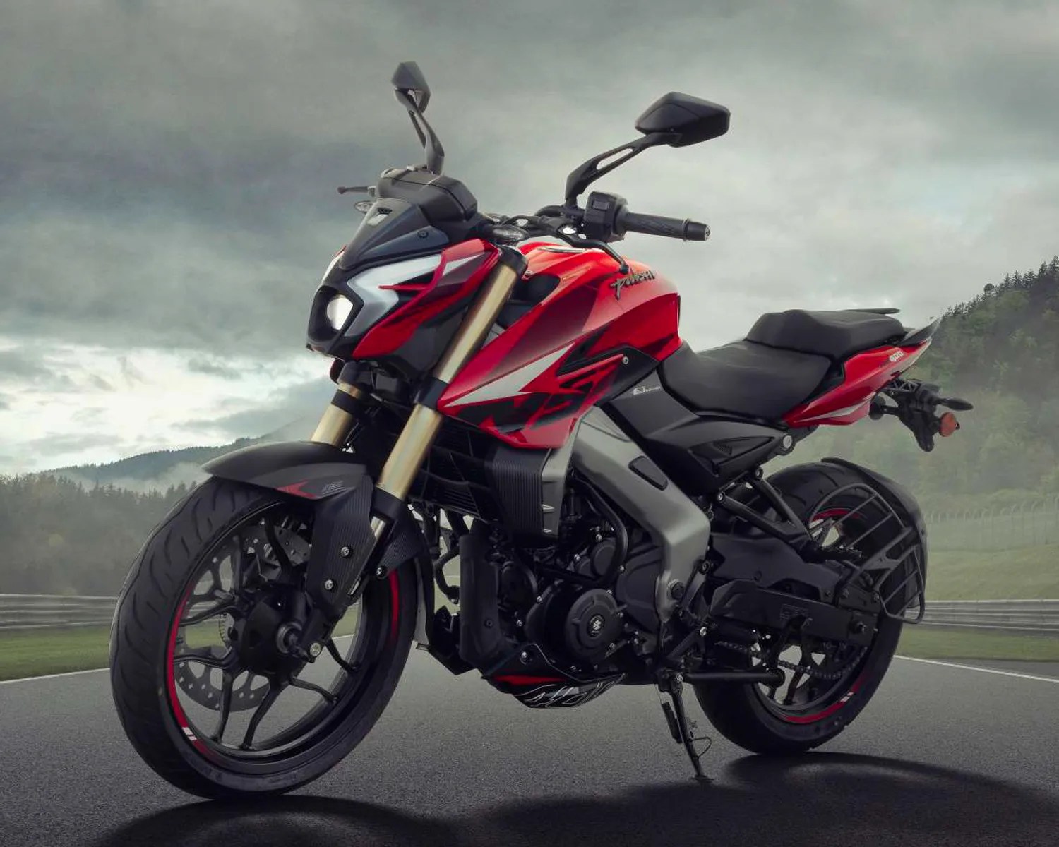 Red and black sport motorcycle with gold front forks parked on a racetrack under cloudy sky.