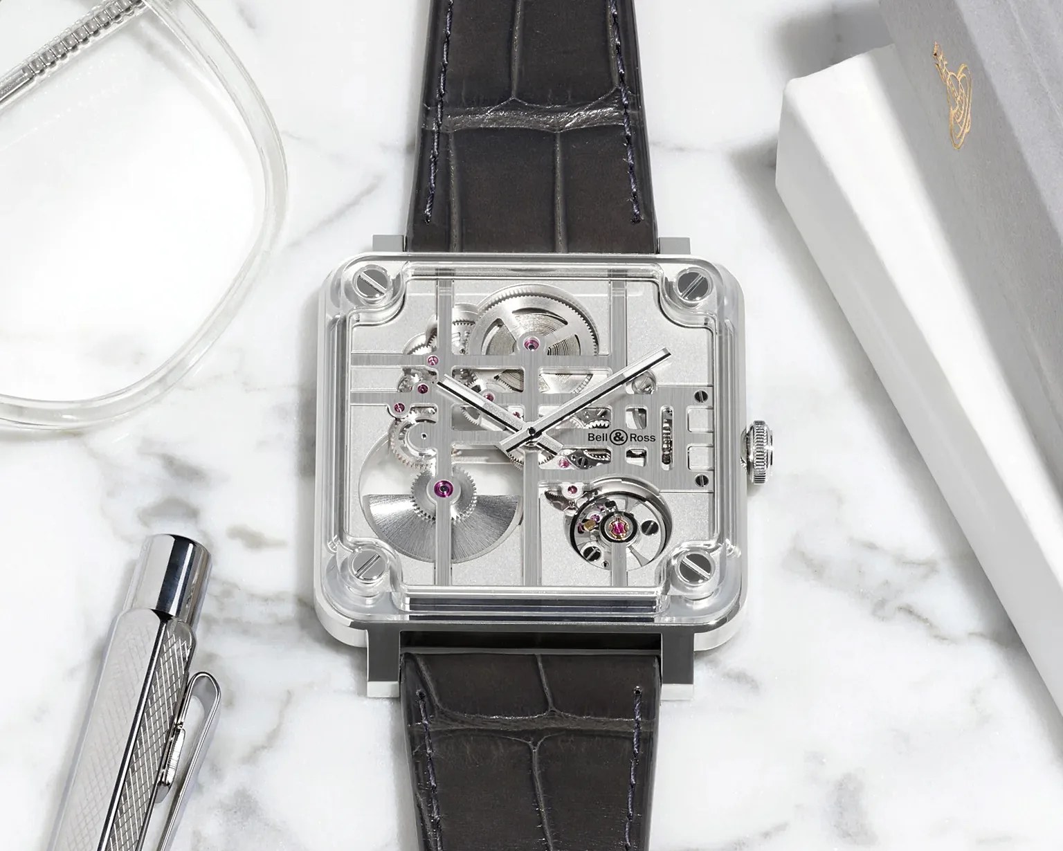 Square Bell & Ross wristwatch with transparent case and visible mechanical gears on a black leather strap.