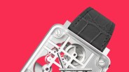 Square silver mechanical watch with visible gears and black leather strap on a red background.