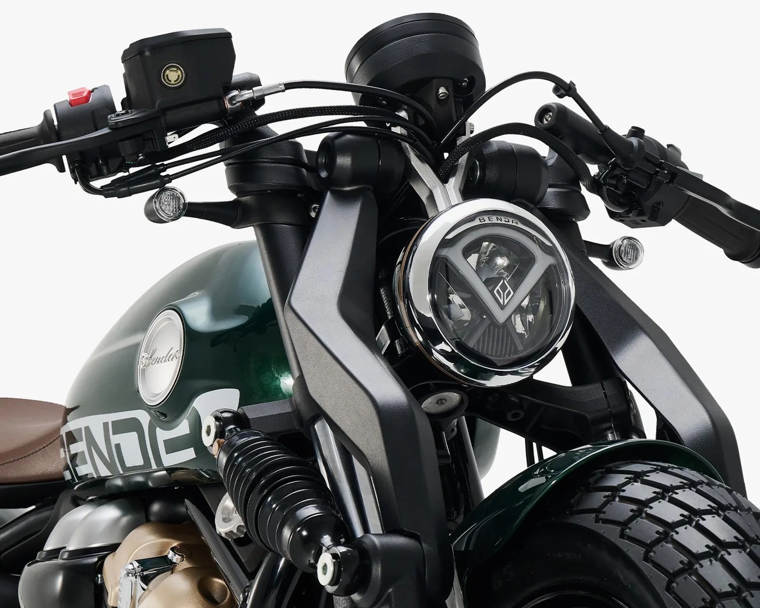 Close-up of a green motorcycle front with round headlight, black suspension, and brown seat.